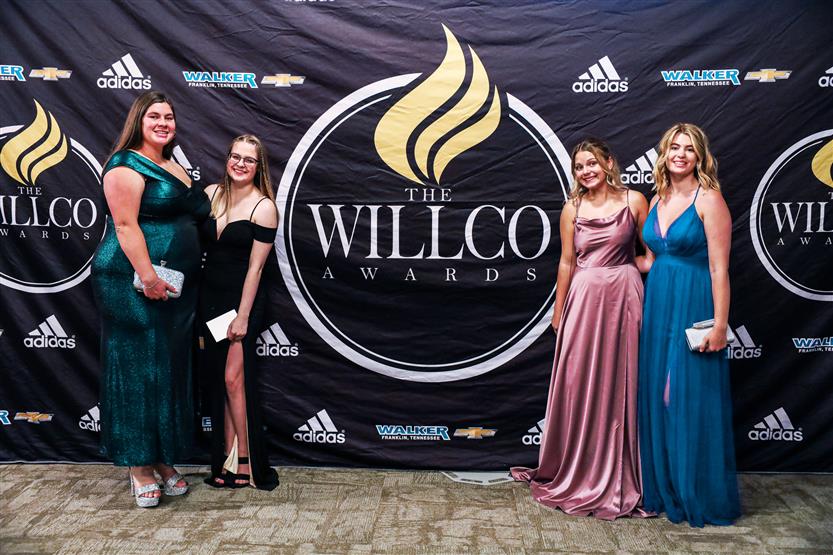Student-athletes stand around a sign for the 2022 WILLCO Awards